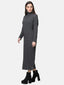 Eine Frau trägt ein langes, geripptes graues Strickkleid mit Rollkragen und langen Ärmeln. Sie steht seitlich und blickt in die Kamera. Ihr Outfit wird durch schwarze Plateaustiefeletten ergänzt, perfekt für eine elegante Herbst- und Wintergarderobe. Der Hintergrund ist schlicht weiß.