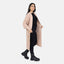 Eine Frau steht vor einem weißen Hintergrund und trägt einen Elara Oversize Cardigan in Hellrosa über einem schwarzen Outfit mit klobigen Stiefeln, blickt in die Kamera und lächelt leicht für einen lässigen Look und maximalen Komfort.