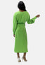 Eine Person mit langen Haaren trägt ein leuchtend grünes, langärmeliges Kleid von Elara, das Eleganz ausstrahlt. Das Kleid hat einen Taillengürtel. Sie ist abgewandt und zeigt den Rücken, während sie weiße High Heels trägt.