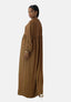 Eine Person steht seitlich vor einem weißen Hintergrund und trägt Elaras langes braunes Damen-Abaya-Maxikleid aus luftigem Polyesterstoff. Das Kleid hat eine hohe Taille und lange Ärmel. Sie trägt Creolen, High Heels und einen Pferdeschwanz, während sie in die Kamera blickt.
