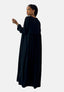 In einem Elara Damen Abaya Maxikleid gekleidet, dreht eine Person ihren Kopf anmutig zur Seite. Ihr kurzes Haar hebt Creolen und ein Armband hervor und erzeugt so vor einem schlichten weißen Hintergrund eine Aura orientalischer Raffinesse.