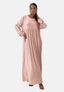 Eine Frau posiert selbstbewusst mit zurückgebundenen Haaren und trägt Elaras langärmeliges Damen Abaya Maxikleid in Pink. Vor einem schlichten weißen Hintergrund verströmt das Kleid einen Hauch orientalischer Raffinesse.