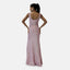 Eine Person steht selbstbewusst mit den Händen in den Hüften und präsentiert ein schimmerndes, rosa, bodenlanges Abendkleid mit tiefem Rückenausschnitt und figurbetonter Silhouette. Der Pferdeschwanz unterstreicht die Eleganz vor dem schlichten weißen Hintergrund und unterstreicht den luxuriösen Reiz des weichen Polyesters.
