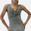 Eine Person trägt ein funkelndes Abendkleid mit einem gedrehten Design auf der Vorderseite. Das ärmellose Kleid hat einen tiefen V-Ausschnitt und ist aus weichem Polyester gefertigt, wodurch es vor dem schlichten weißen Hintergrund einen eleganten und raffinierten Look unterstreicht.