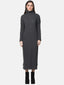 Vor einem schlichten weißen Hintergrund steht eine Frau, bekleidet mit einem langen, gerippten Strickkleid, einem dunkelgrauen Rollkragenpulloverkleid und schwarzen Stiefeletten – perfekt für die Herbst- und Wintergarderobe.