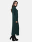 Seitenansicht einer Person, die ein langes, dunkelgrünes Strickkleid mit Rollkragen und schwarzen Plateaustiefeln trägt. Dieses gerippte Kleid, perfekt für die Herbst- und Wintergarderobe, hat lange Ärmel und einen kleinen Schlitz am unteren Saum. Der Hintergrund ist schlicht weiß.