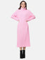 Eine Person in einem langen rosa Rollkragen-Strickkleid steht vor einem schlichten Hintergrund. Das gerippte Kleid hat lange Ärmel und passt perfekt zu schwarzen Stiefeletten. Die Hände sind in die Hüften gestemmt, und die Frau lächelt herzlich. Sie präsentiert eine stilvolle Ergänzung ihrer Herbst- und Wintergarderobe.
