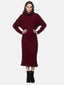 Vor schlichtem Hintergrund präsentiert eine Frau ein dunkelrotes Rippstrickkleid – ein Must-have für jede Herbst- und Wintergarderobe. Der Rollkragen und die langen Ärmel verleihen Eleganz, während schwarze Stiefeletten das Outfit komplettieren. Die selbstbewusst auf die Hüften gestemmten Hände unterstreichen die selbstbewusste Eleganz des Ensembles.