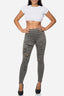Eine Frau steht mit den Händen in den Hüften und präsentiert Elaras weißes bauchfreies Top und ihre olivgrünen Skinny Jeans im Used-Look, kombiniert mit schwarzen High Heels vor einem schlichten weißen Hintergrund.
