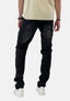 Eine Person in einem hellen Elara-Shirt, schwarzen Jeans und weißen Turnschuhen steht mit dem Rücken zur Kamera vor einem schlichten, hellen Hintergrund.