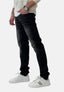 Abgebildet ist ein Mann von der Taille abwärts in schwarzen Elara-Jeans im coolen Waschlook, kombiniert mit einem weißen Langarmshirt und weißen Sneakers mit schwarzen Streifen vor einem schlichten weißen Hintergrund.