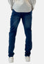 Eine Person, von hinten vor einem schlichten weißen Hintergrund gesehen, trägt ein weißes Hemd von Elara, dunkelblaue Jeans im Waschlook mit bequemer Passform für lässigen Stil und weiße Turnschuhe.