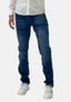 Eine Person präsentiert Elaras Bluejeans im modernen Waschlook, kombiniert mit einem weißen Hemd und Sneakers vor einem schlichten Hintergrund. Das zugeschnittene Bild hebt die Passform und den Stil des Unterkörpers und der Beine hervor.