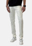 Eine Person präsentiert Elara Slim-Fit-Jeans im modernen Waschlook mit weißen Sneakers, schwarzem T-Shirt, Uhr und Armband vor einem schlichten hellen Hintergrund. Gezeigt wird nur die untere Hälfte des Outfits.