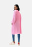 Eine Person steht mit abgewandtem Gesicht da und blickt über die Schulter. Sie trägt einen lässigen Elara-Look mit einer langen, übergroßen rosa Strickjacke, Bluejeans und rosa-weißen Turnschuhen vor einem schlichten weißen Hintergrund.
