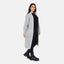 Eine Person steht vor einem weißen Hintergrund und trägt einen übergroßen hellgrauen Elara-Cardigan über einem schwarzen Outfit mit klobigen schwarzen Stiefeln und blickt leicht zur Seite, um einen lässigen Look und maximalen Komfort zu erzielen.