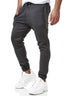 Eine Person trägt die dunkelgraue Jogginghose „Elara“ mit Taschen, Kordelzugbund und flexibler Passform und kombiniert sie mit weißen Sneakers vor weißem Hintergrund. Die Jogginghose ist ideal fürs Fitnessstudio. Der Oberkörper ist teilweise außerhalb des Bildes.