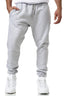 Eine Person in der hellgrauen Jogginghose Elara mit flexibler Passform und weißen Turnschuhen steht mit einer Hand in der Tasche vor einem weißen Hintergrund.