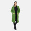 Eine Frau trägt eine übergroße grüne Elara-Strickjacke für maximalen Komfort über einem schwarzen Oberteil und einer schwarzen Hose, kombiniert mit Schnürstiefeln. Ihr langes dunkles Haar ist zurückgekämmt, und ihre Hände ruhen lässig in den Taschen der Strickjacke für einen lässigen Look.
